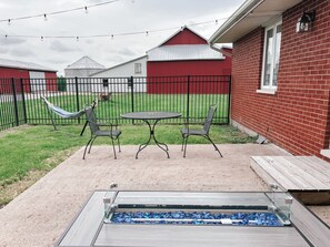 Un patio con una mesa y sillas, una hamaca y un expositor de vidrio con objetos azules.