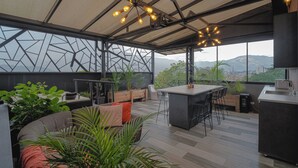 Una cocina moderna con barra, ventanas amplias y vistas a la ciudad y montañas.