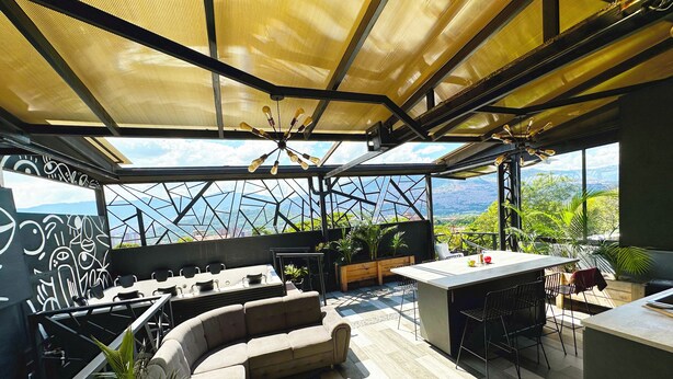 Un espacio de comedor al aire libre de diseño moderno, con una mesa grande, varias sillas y una zona de estar con sofá.