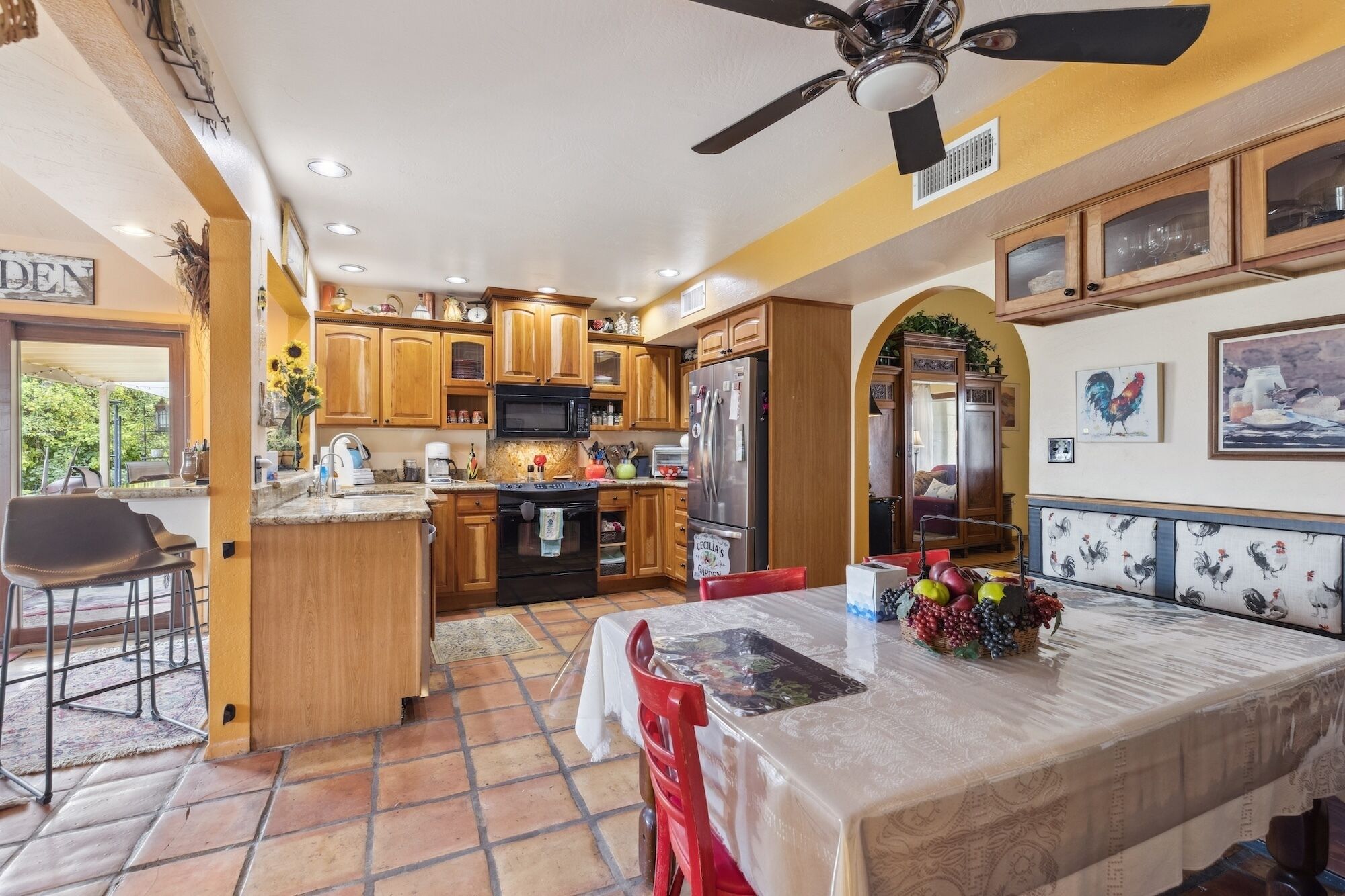 A kitchen with wooden cabinets, a refrigerator, and a dining area with a table and chairs.