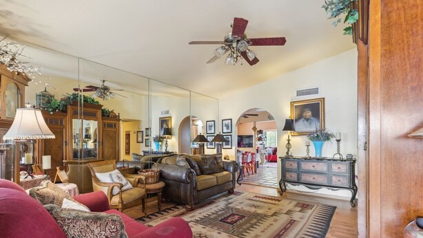 A spacious living room with a red sofa, leather armchairs, a patterned rug, and a ceiling fan. - Mesa Meadow Retreat (Mesa)