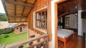 Une cabane en bois dotée d’un balcon, d’une petite dépendance attenante et d’une chambre à coucher avec un lit.