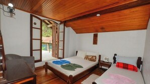 Une chambre avec un plafond en bois, un lit avec un matelas blanc, une table de chevet avec une radio et une chaise.