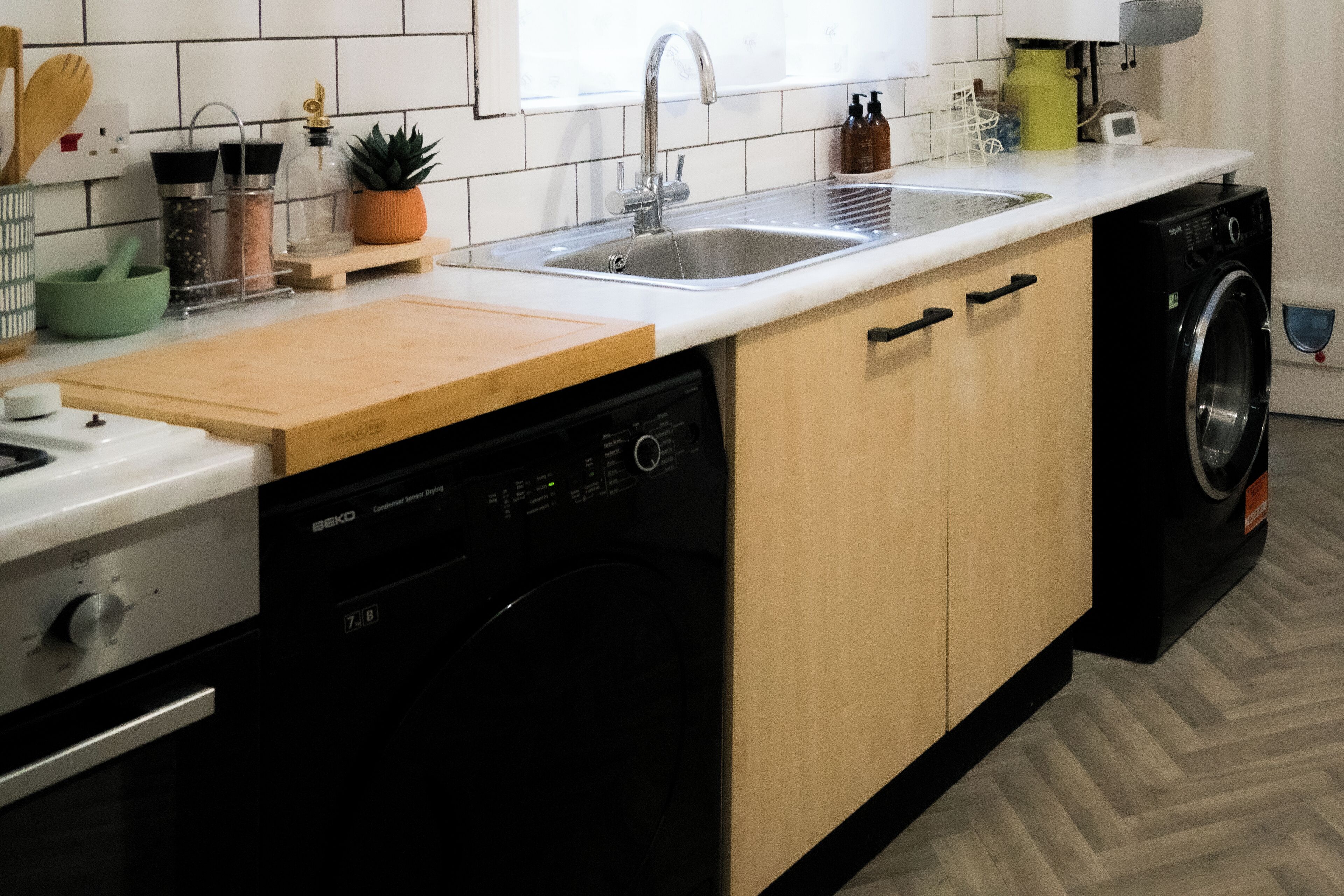Una cucina con lavastoviglie, lavello, piano di lavoro in legno e lavatrice.