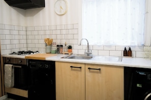 A kitchen with white tiled backsplash, a sink, a stove, and a dishwasher. - Centre of Whitley Bay Short & Long Stay (Whitley Bay)