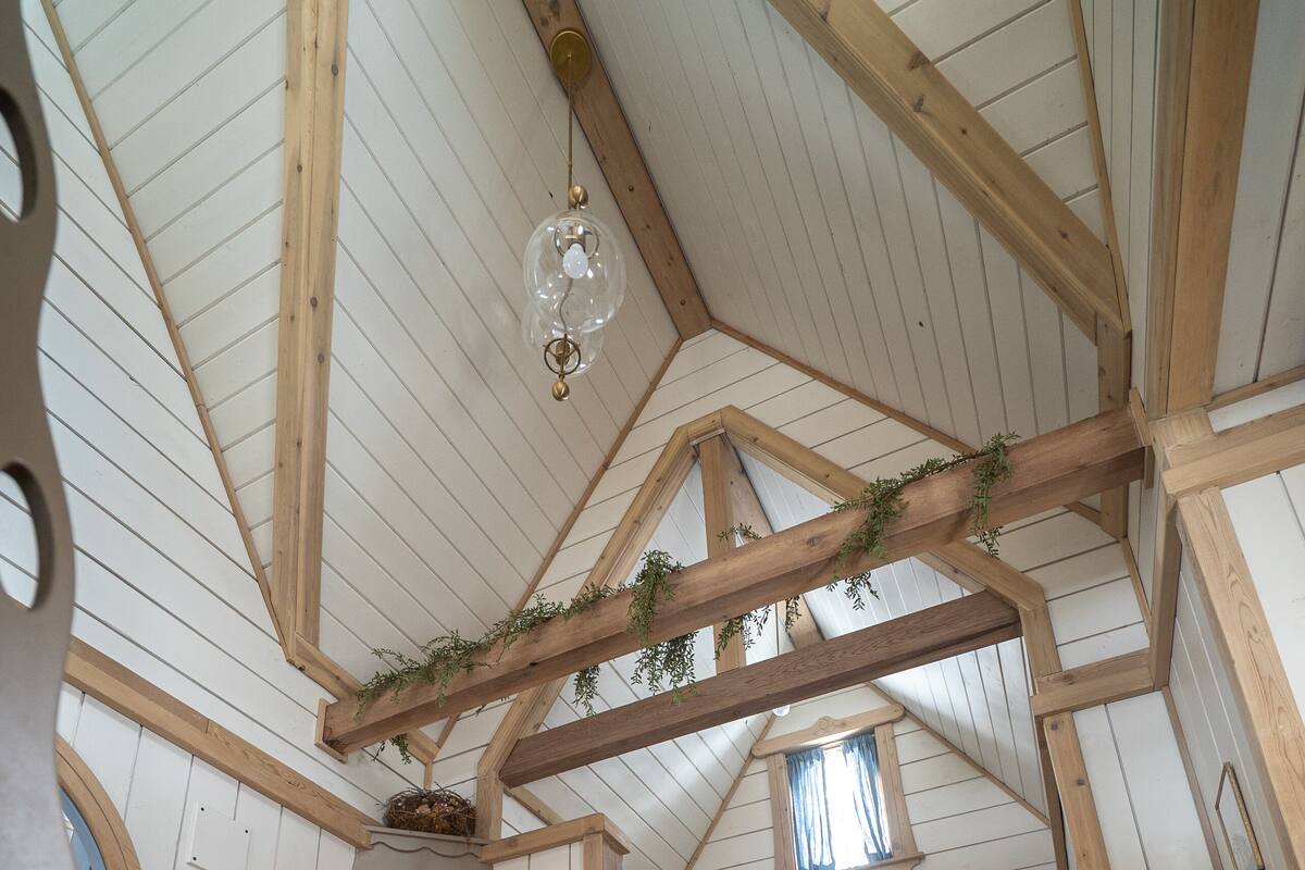 A cozy attic bedroom with a wooden ladder, a fireplace, and a bunk bed.
