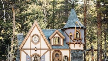A rustic cabin with a stone facade, a conical roof, and a circular tower.