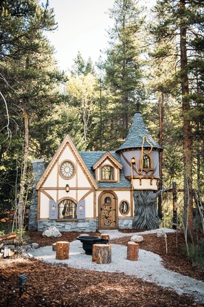 A rustic cabin with a stone facade, a conical roof, and a circular tower. - Charmed Resorts (Blairmore)
