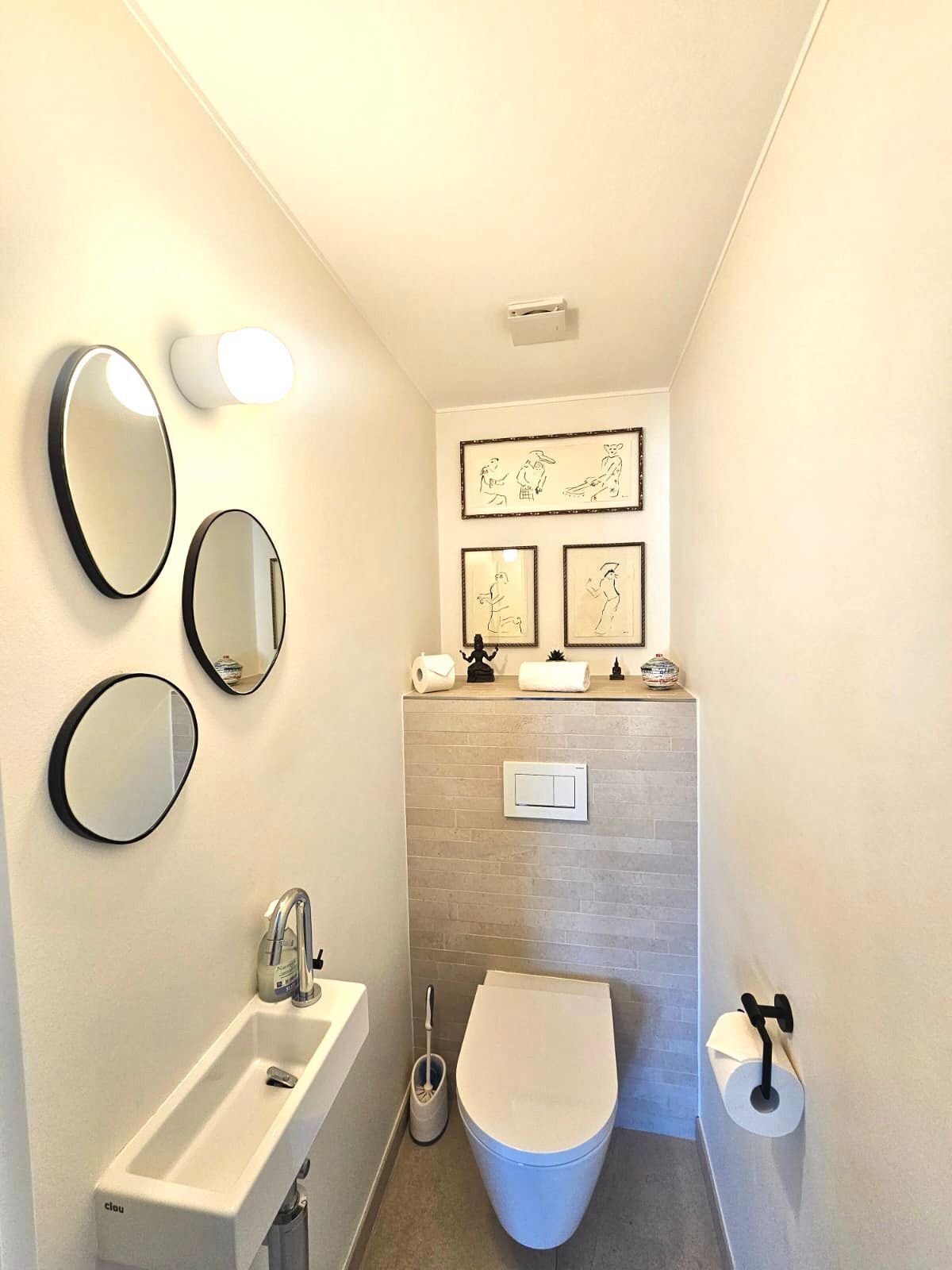 A compact bathroom with a sink, toilet, and three wall-mounted mirrors.