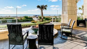 Une terrasse extérieure avec des fauteuils en osier, un petit foyer et une vue sur la mer.