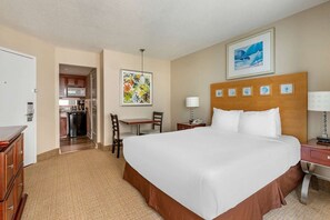 A hotel room with a large bed, a desk, a chair, a small table, a lamp, a telephone, and a painting on the wall. - Virginia Beach | Coastal Getaway | Resort Pool & Beach Access (Virginia Beach)