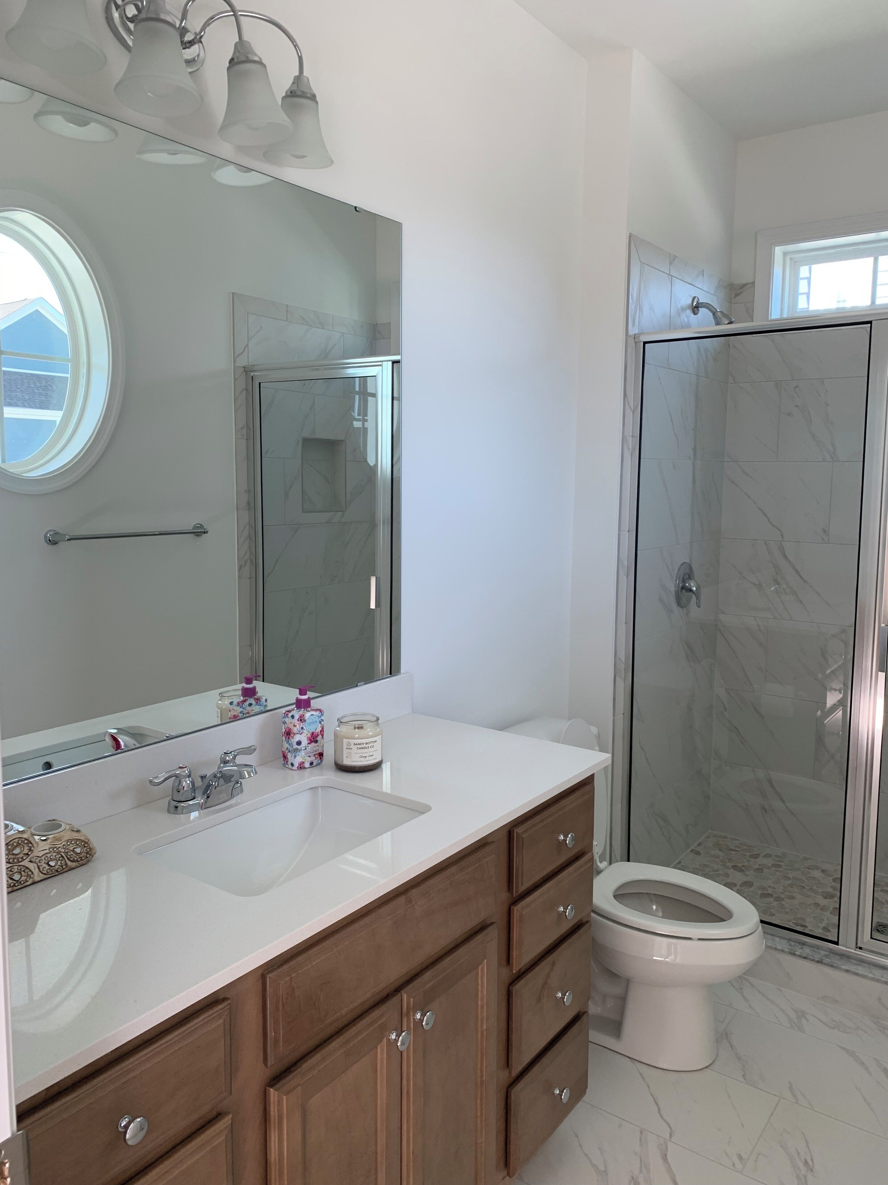 A bathroom with a white vanity, a large mirror, a glass shower enclosure, and a toilet.