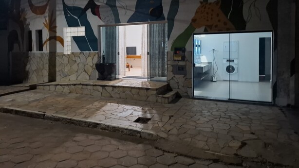 L'ingresso di un hotel con facciata in pietra, un'ampia pianta in vaso e vista su una stanza con una lavatrice.
