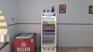 Una macchina distributrice con un'etichetta rossa, un frigorifero con un'etichetta bianca e una parete con due quadri incorniciati.