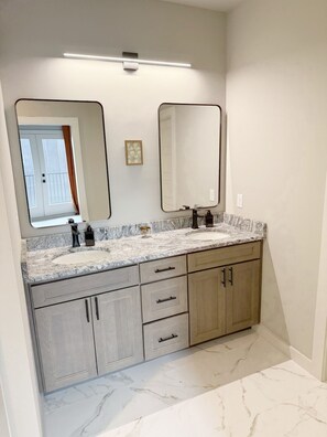 A bathroom with a marble sink, double mirrors, and wooden cabinets.