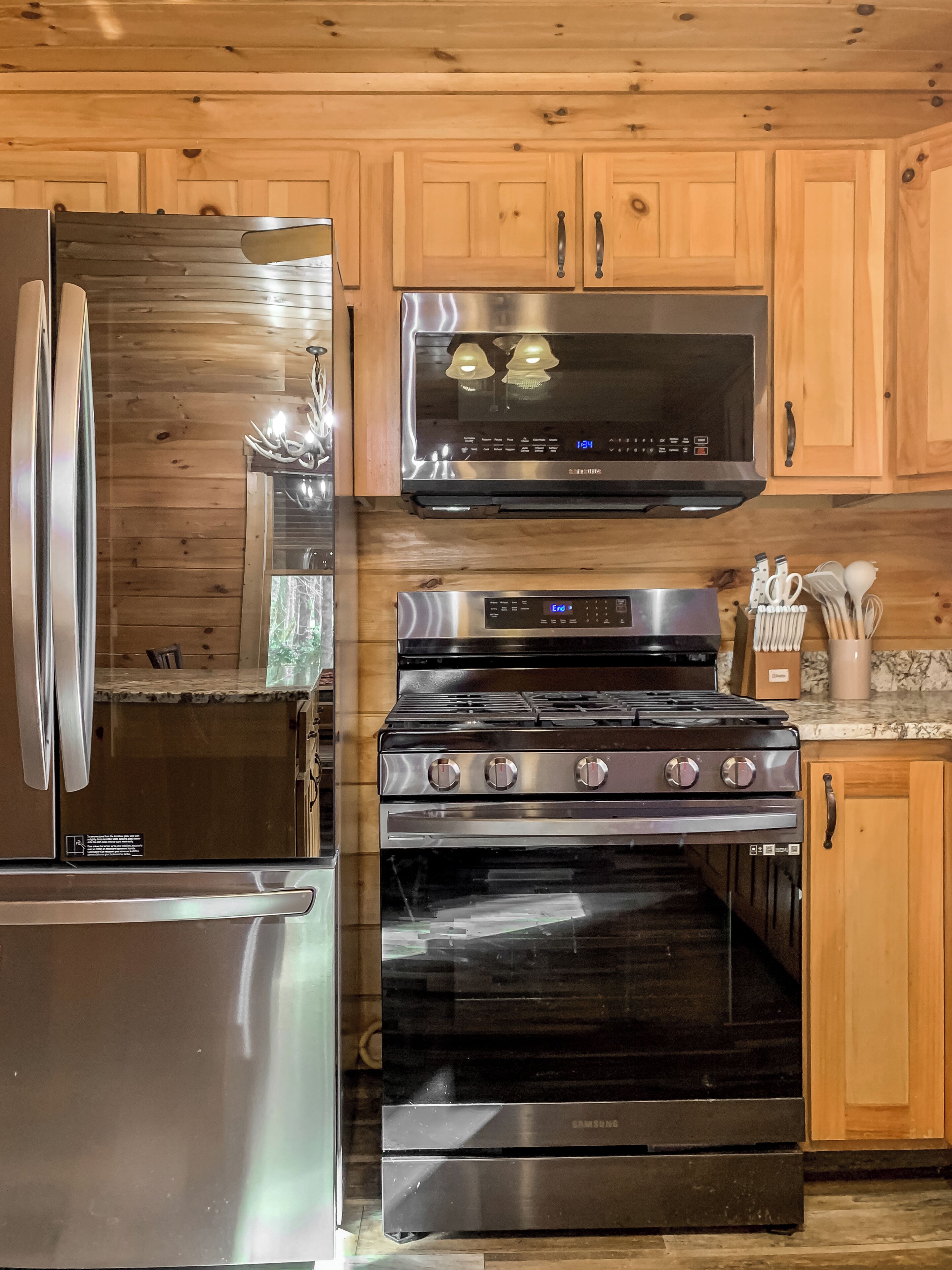 A kitchen with wooden cabinets, a stainless steel refrigerator, a microwave, a stove, and an oven.