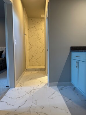 Stylish hallway leads to a bathroom with a marble backsplash.