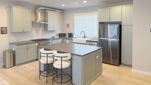 A modern kitchen with grey cabinets, stainless steel appliances, and a central island with bar stools. - 2BR 2.5 Downtown Oasis Full Kitchen, Pet Friendly, Close to Silos Food Hall (Easley)