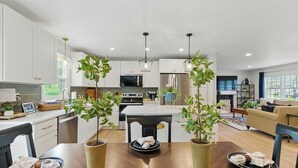 Una cocina moderna con armarios blancos, una isla central y lámparas colgantes.