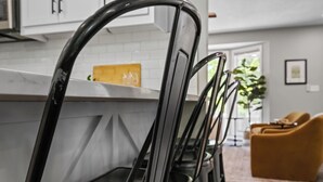 A kitchen with white cabinets, a countertop, and a chair with a black frame. - Once Upon A Trail: Direct Trail Access >1mi to OZ Bike Park >Hot Tub >Theater Rm (Bella Vista)