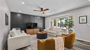 A modern living room with a sofa, ottoman, and a television. - Once Upon A Trail: Direct Trail Access >1mi to OZ Bike Park >Hot Tub >Theater Rm (Bella Vista)