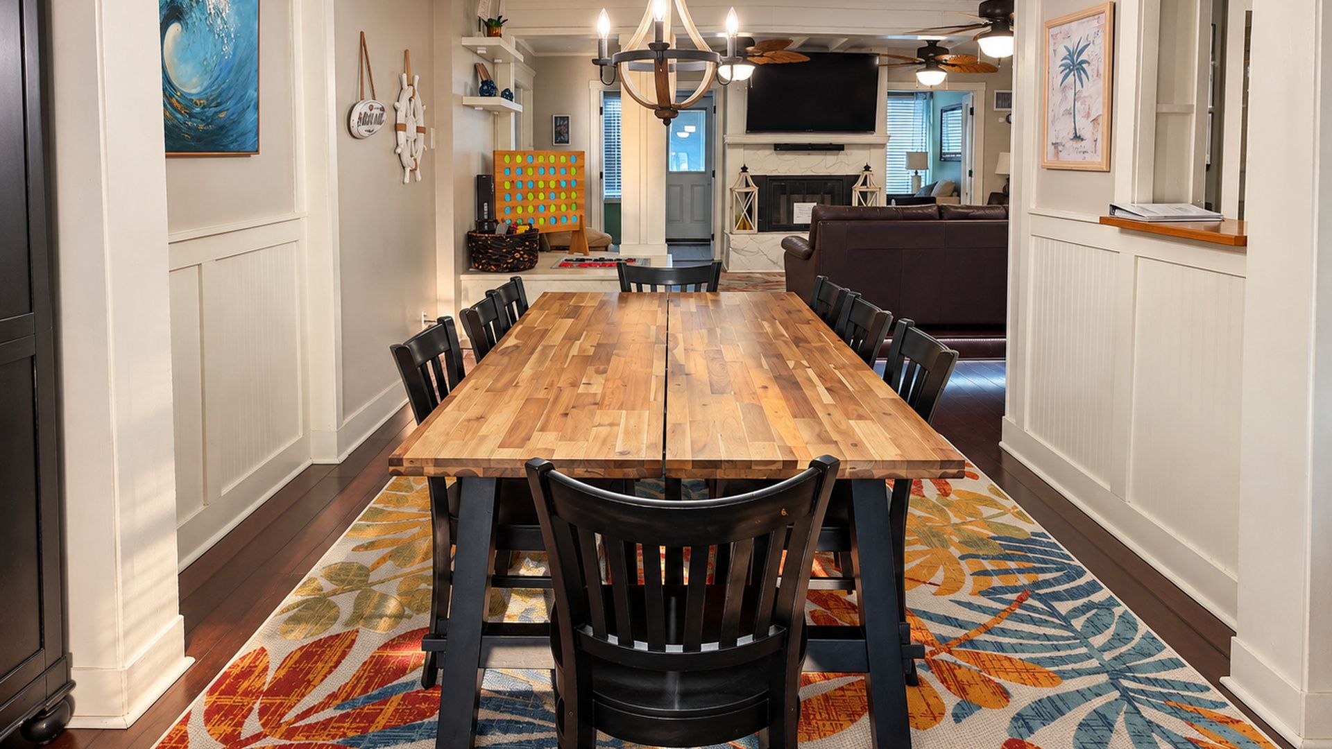 A dining area with a long wooden table, black chairs, and a patterned rug.