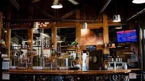 Een bar met een houten interieur, een plafondventilator en een menubord.