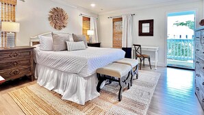 Un dormitorio con una cama grande, un escritorio, una silla y vistas al exterior.