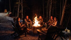 A group of people around a campfire in a forest setting.