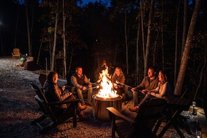 A group of people around a campfire in a forest setting.