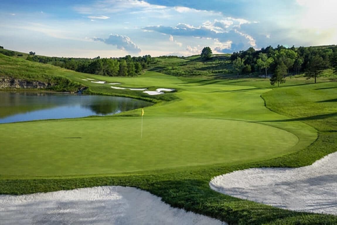 Un campo da golf con uno stagno, bunker di sabbia e un bastoncino da segnalazione.