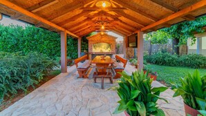 An outdoor patio with a brick oven, stone flooring, wooden furniture, and lush greenery. - Villa Lavandis with Jacuzzi and 50m2 Pool (Vinjani Donji)