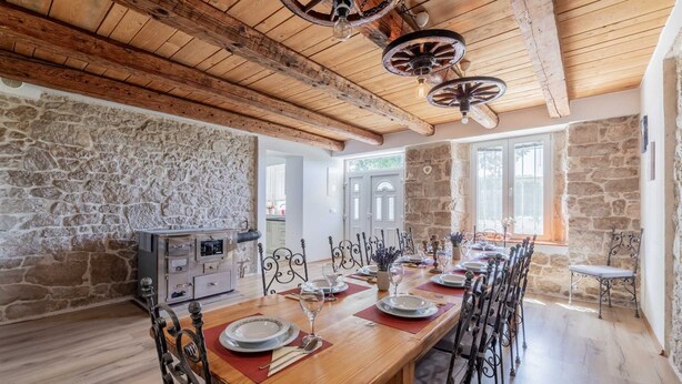A dining area with a wooden table set for six, stone walls, and a rustic ceiling with wooden beams. - Villa Lavandis with Jacuzzi and 50m2 Pool (Vinjani Donji)