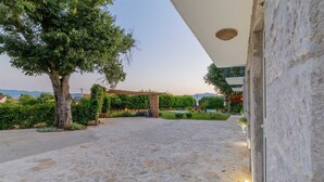 A stone-paved courtyard with a large tree, a pergola, and a view of the sea. - Villa Lavandis with Jacuzzi and 50m2 Pool (Vinjani Donji)