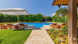 A swimming pool with lounge chairs and umbrellas, surrounded by a well-maintained garden and a stone pathway. - Villa Lavandis with Jacuzzi and 50m2 Pool (Vinjani Donji)