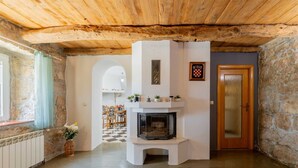 A room with a fireplace, stone walls, wooden ceiling, and a checkered floor. - Villa Lavandis with Jacuzzi and 50m2 Pool (Vinjani Donji)