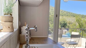 Una cocina con un lavamanos blanco, encimera de madera y armarios. Se ve una piscina y un área de estar al aire libre.