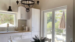 Una cocina moderna con armarios blancos, una pared de acento de piedra y un comedor con una mesa y sillas blancas.