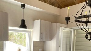 Una cocina con ventana, pileta, alacenas, una mesa y una silla.
