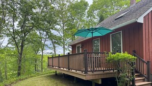 En træterrasse med grøn parasol, en trappe og et hus med rød facade.