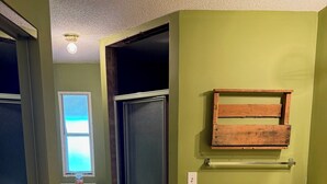 A bathroom with green walls, a wooden medicine cabinet, a large mirror, and a sink with toiletries.
