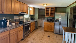 A kitchen with wooden cabinets, a stainless steel refrigerator, a microwave, a stove, and a sink.