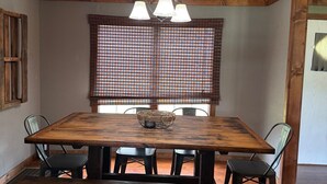 A dining area with a wooden table, black chairs, and a hanging light fixture.