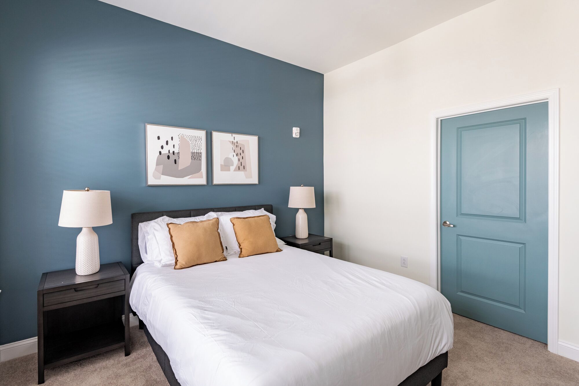Une chambre à coucher avec un lit, deux tables de chevet, deux lampes et une porte.