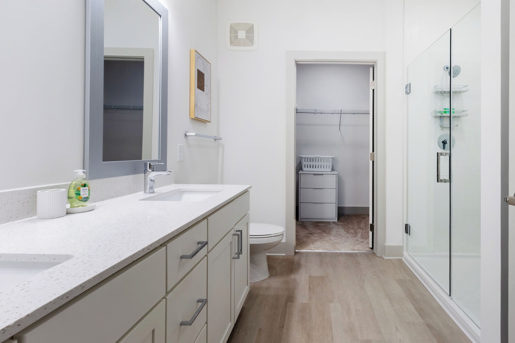A modern bathroom with a white countertop, a mirror, a toilet, and a shower area.