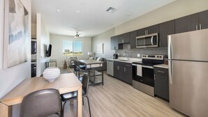 A modern kitchen with dark cabinets, stainless steel appliances, and a dining area with a wooden table and chairs. - Landing Apartments Glendale (Glendale)