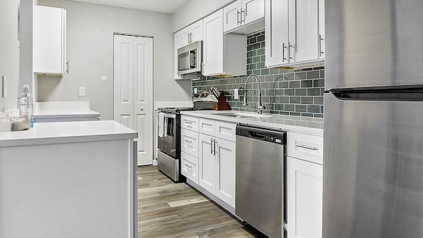 A modern kitchen with white cabinets, stainless steel appliances, and a tiled backsplash. - Landing Apartments Indy (Indianapolis)