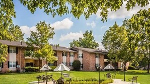 A residential building with a brick facade, multiple windows, and a well-maintained lawn with outdoor seating. - Landing Apartments Indy (Indianapolis)