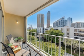Enjoy the city view from this balcony with a seating area and potted plant.