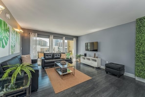 Relax in a stylish living room with a black leather sofa, flat-screen TV, and city views.